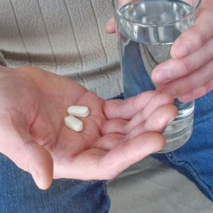 bigstock-man-holding-pills-and-a-glass-449988441_1_621x621