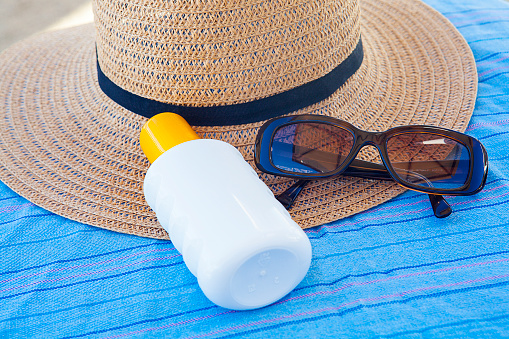 Sunscreen, hat and glasses on beach . Day with sunny in Çeşme,Turkey.