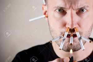 148253578-unshaven-man-sternly-looks-into-the-camera-intending-to-light-a-lot-of-cigarettes-at-once-which